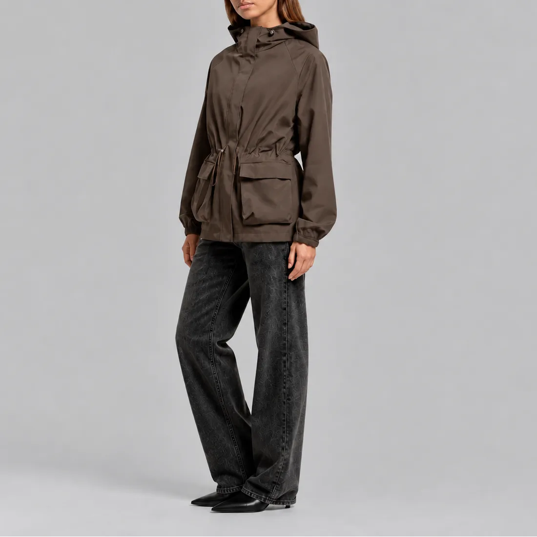 Side view of the brown jacket styled with dark jeans, showing the hood and cinched waist detail
