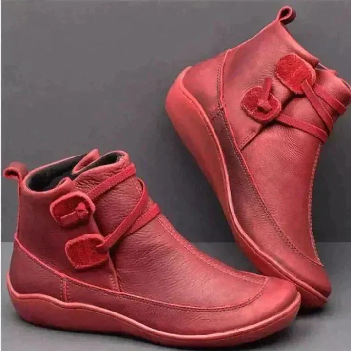 Pair of red leather ankle boots with stitched panels, decorative toggle strap and chunky slip-on sole
