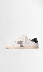 Side profile of a white leather trainer with a grey suede clover motif and black leather heel tab