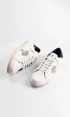 Top-down view of a pair of white leather trainers showing laces and the distressed off-white sole