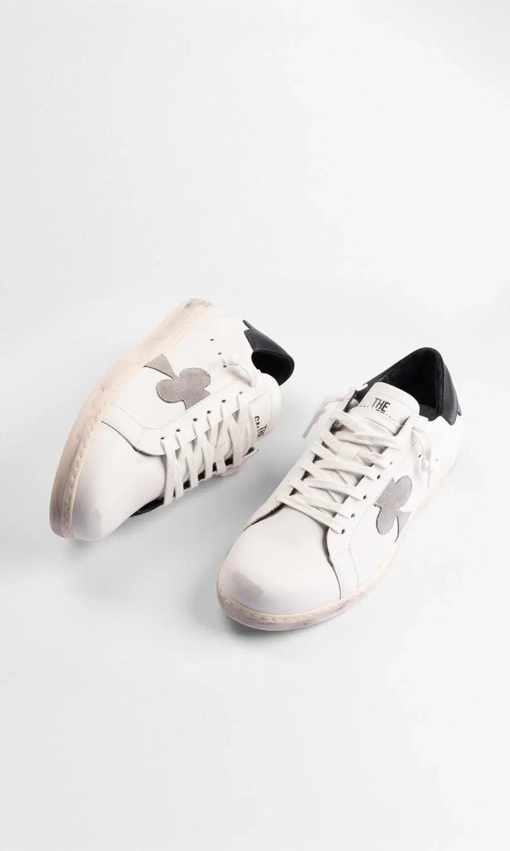 Top-down view of a pair of white leather trainers showing laces and the distressed off-white sole