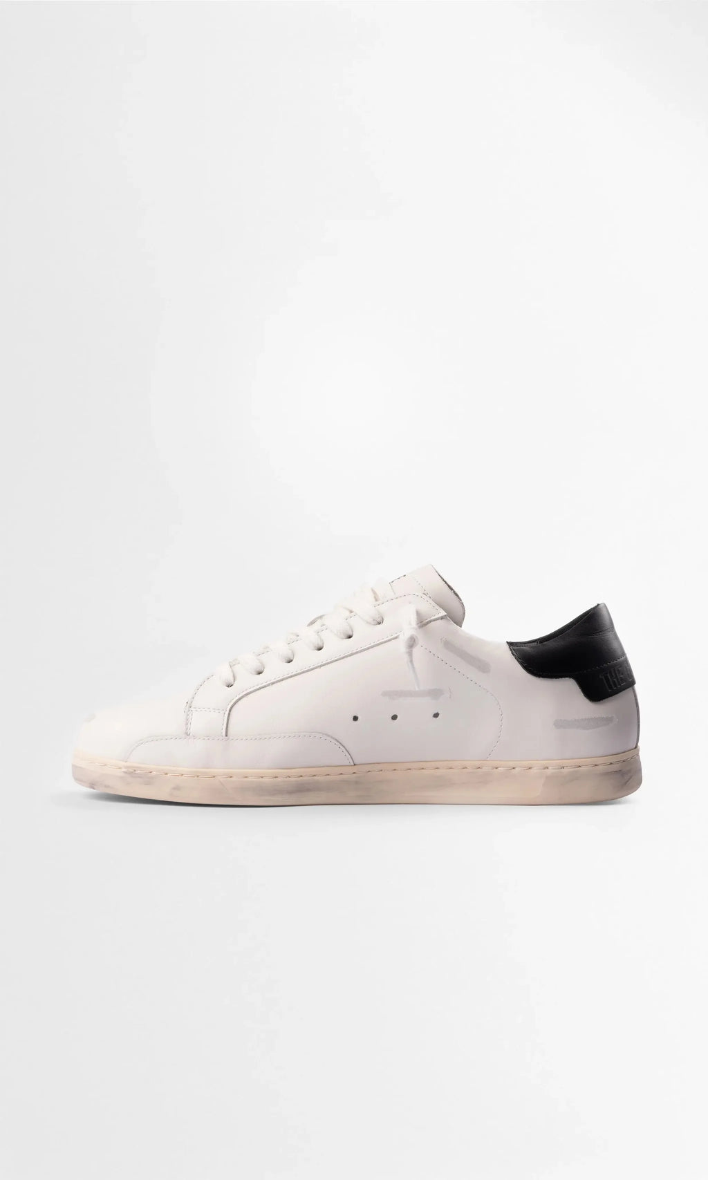 Full side view of the trainer showing the white leather upper, black heel panel and embossed branding