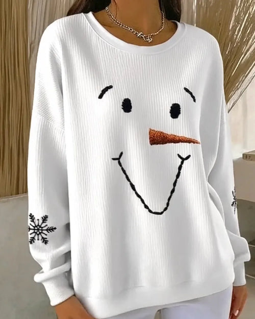 Close-up of the embroidered snowman face with black eyes, brows, smile and an orange carrot nose on ribbed white fabric