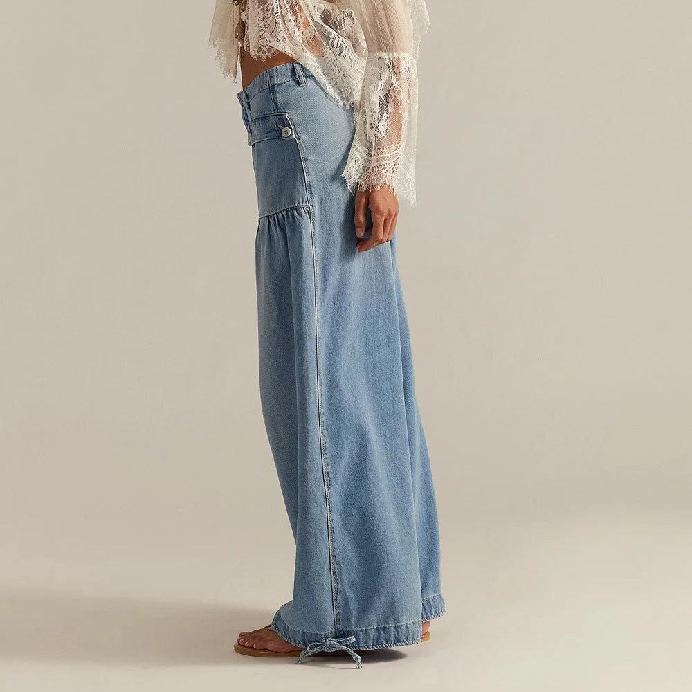Side profile showing the flowy drape and drawstring cuff hem of the wide-leg denim trousers