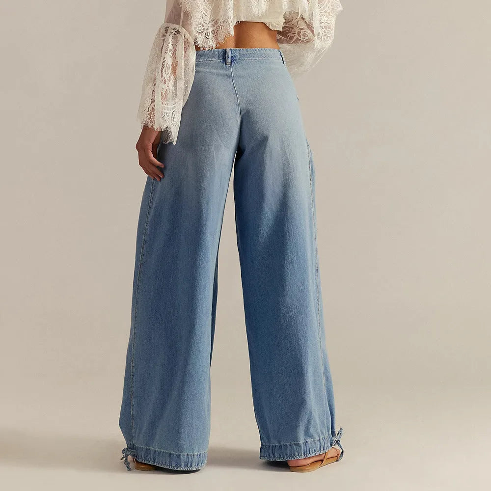 Back view highlighting the relaxed wide leg and gathered yoke seam of the light wash denim trousers