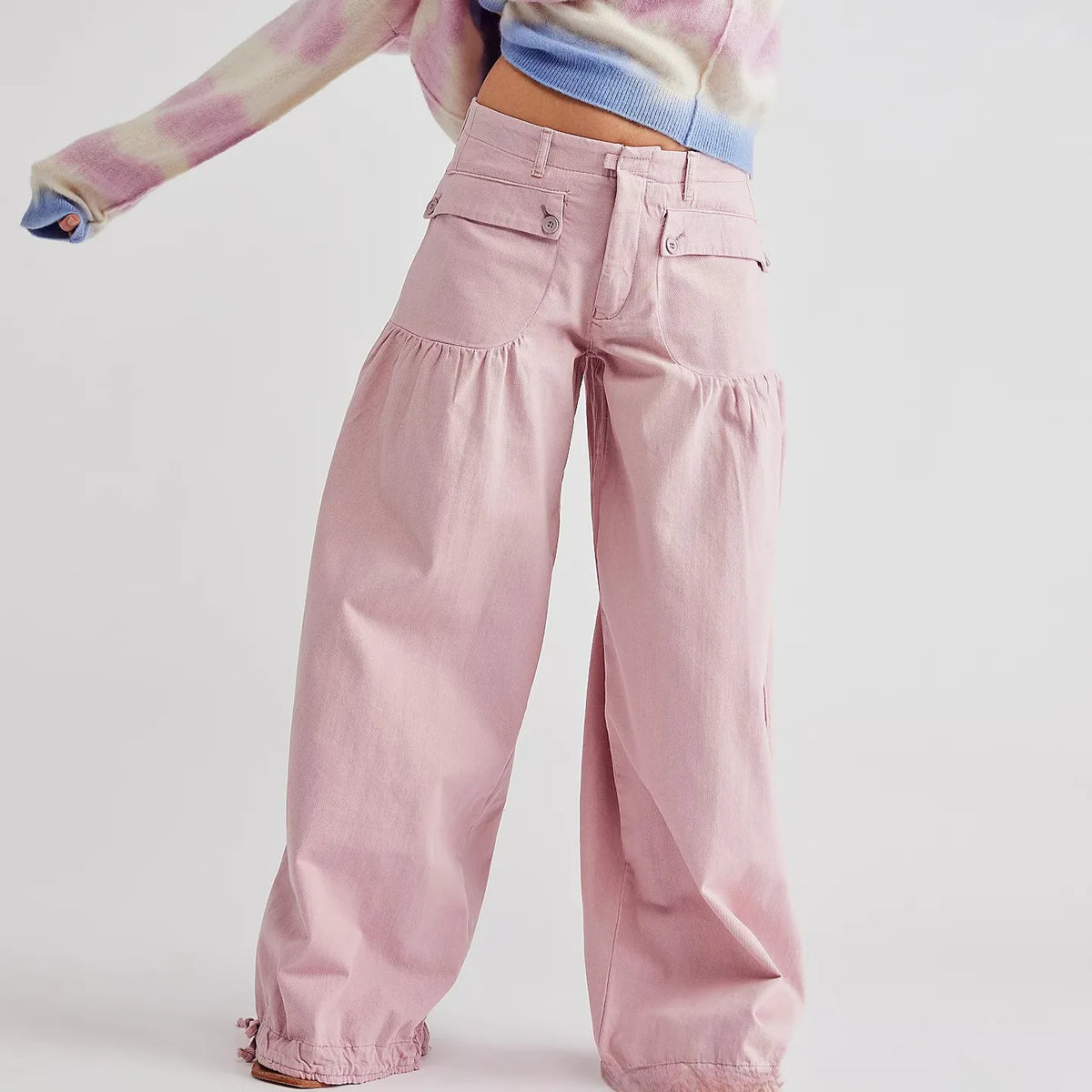 Front view of pale pink cotton wide-leg trousers with buttoned pockets and gathered hip panels