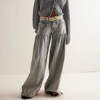 Front view of light grey washed denim wide-leg trousers with gathered pockets, styled with a chunky knit cardigan