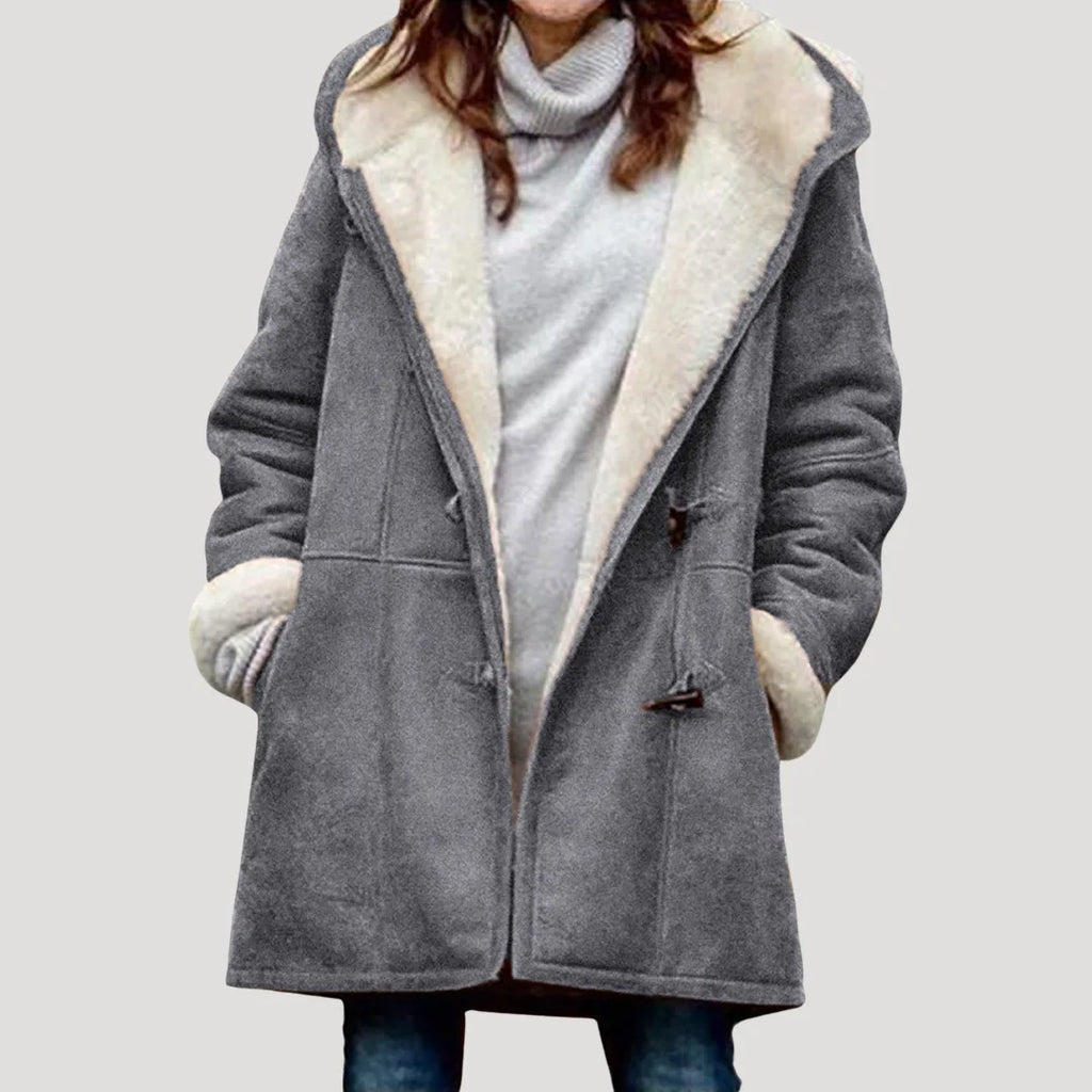 Grey duffle coat with cream borg lining, hood up slightly, worn over a grey polo neck jumper