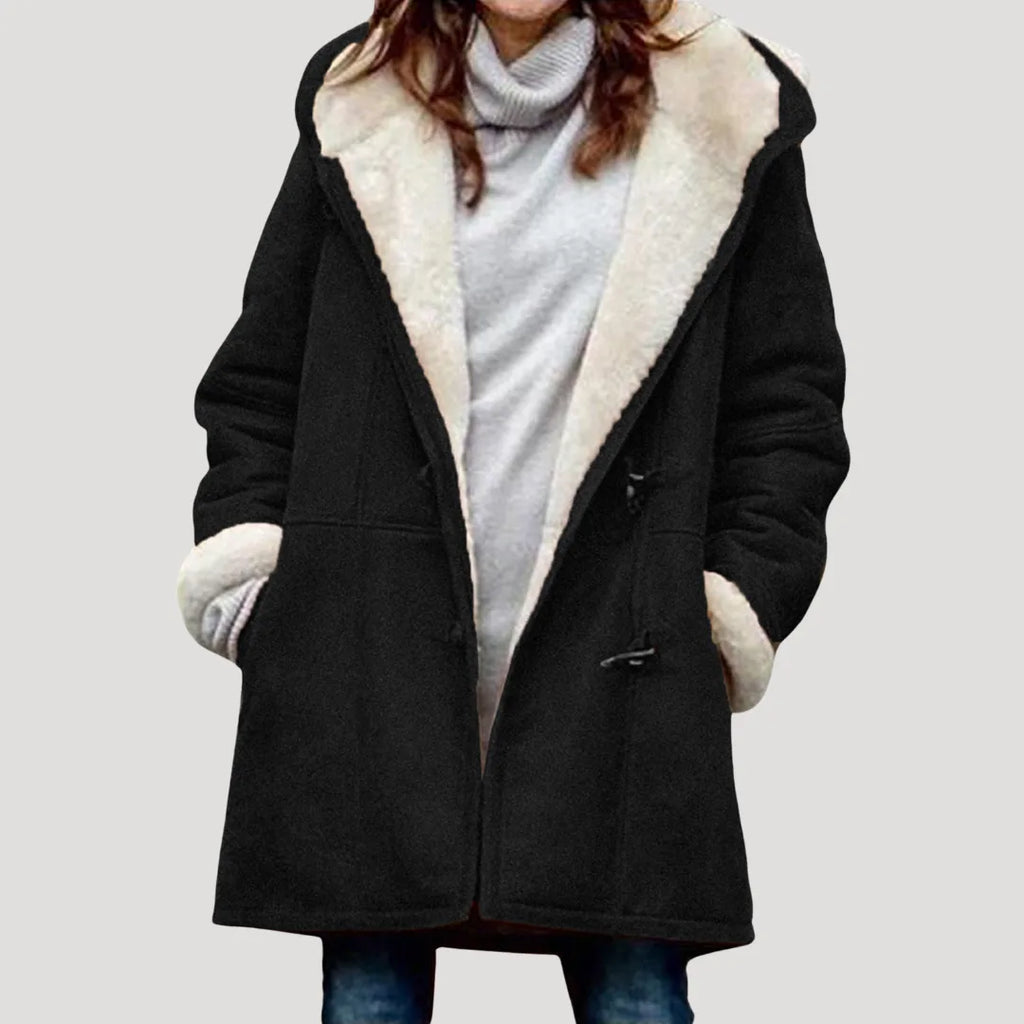 Black duffle coat with cream fleece-lined hood and collar, shown open over a grey knit jumper