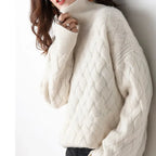Close-up side view of a cream cable-knit polo neck jumper with oversized sleeves and ribbed collar
