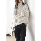 Woman wearing a cream woven-pattern polo neck jumper with dark jeans and a white crossbody bag