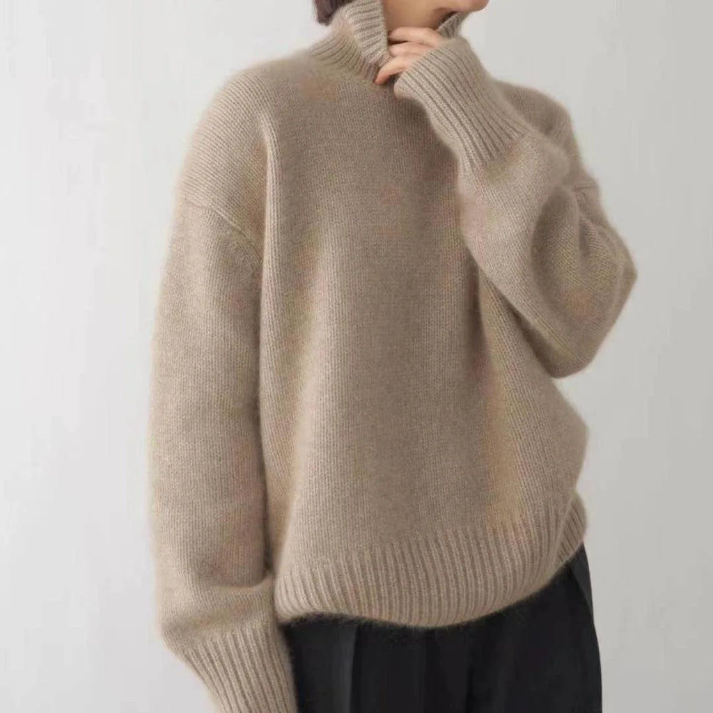Side view of a beige polo neck jumper with ribbed high collar and oversized sleeves worn over black trousers