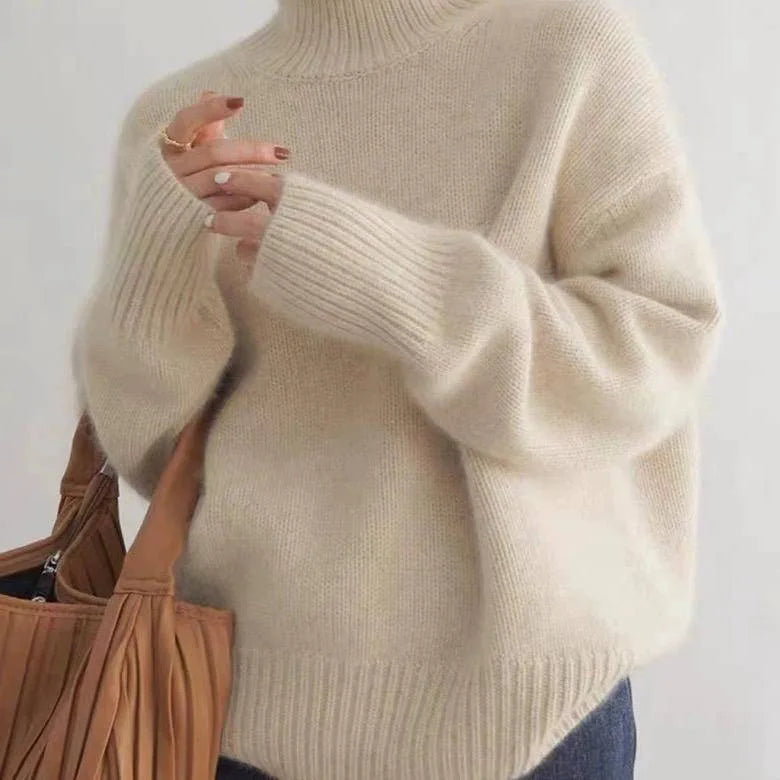 Cream coloured polo neck jumper with ribbed cuffs, worn with a red ring on the hand near the collar