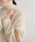 Close up side profile of ribbed sleeve detail on a cream oversized polo neck jumper
