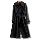 Black double-breasted trench coat with belted waist and checked lining peeking at the hem