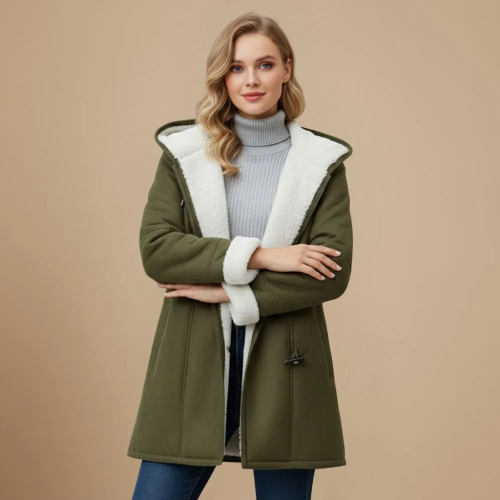 Front view of the olive green duffle coat with arms crossed, showing the cream fleece cuffs and hood
