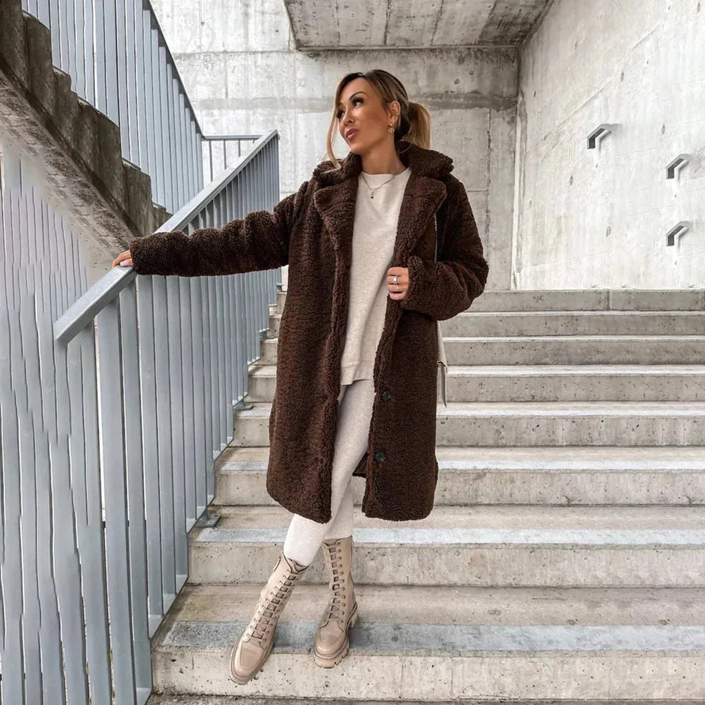 Woman on stairs in a dark brown teddy coat with hood, paired with cream tights and lace-up boots