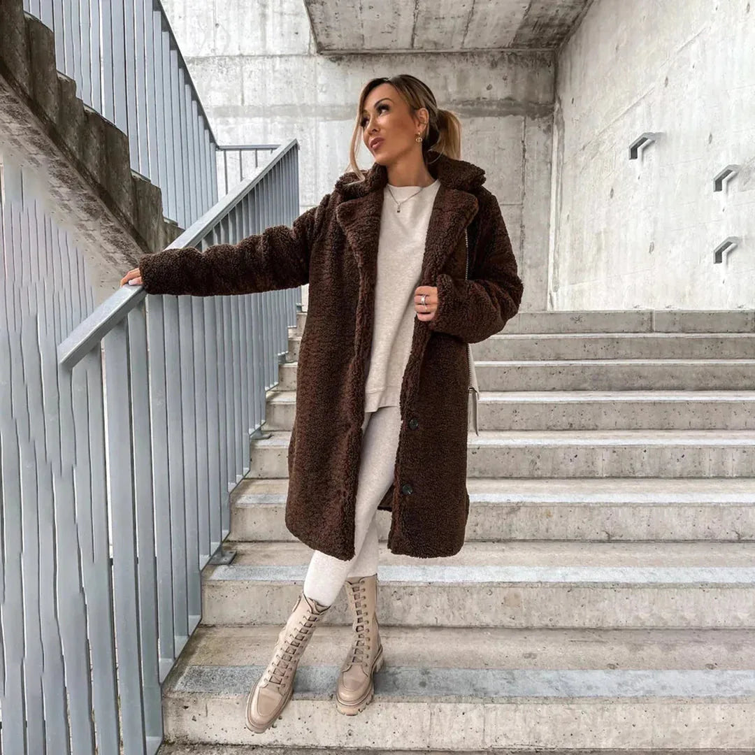 Woman on stairs in a dark brown teddy coat with hood, paired with cream tights and lace-up boots
