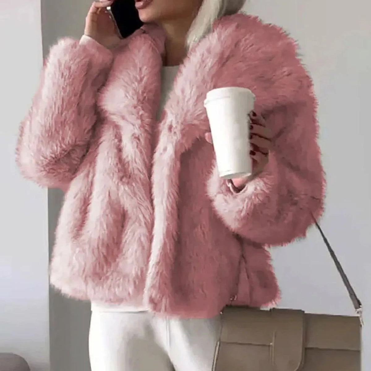 Pink faux fur cropped jacket with open front, worn over a white outfit while holding a coffee cup