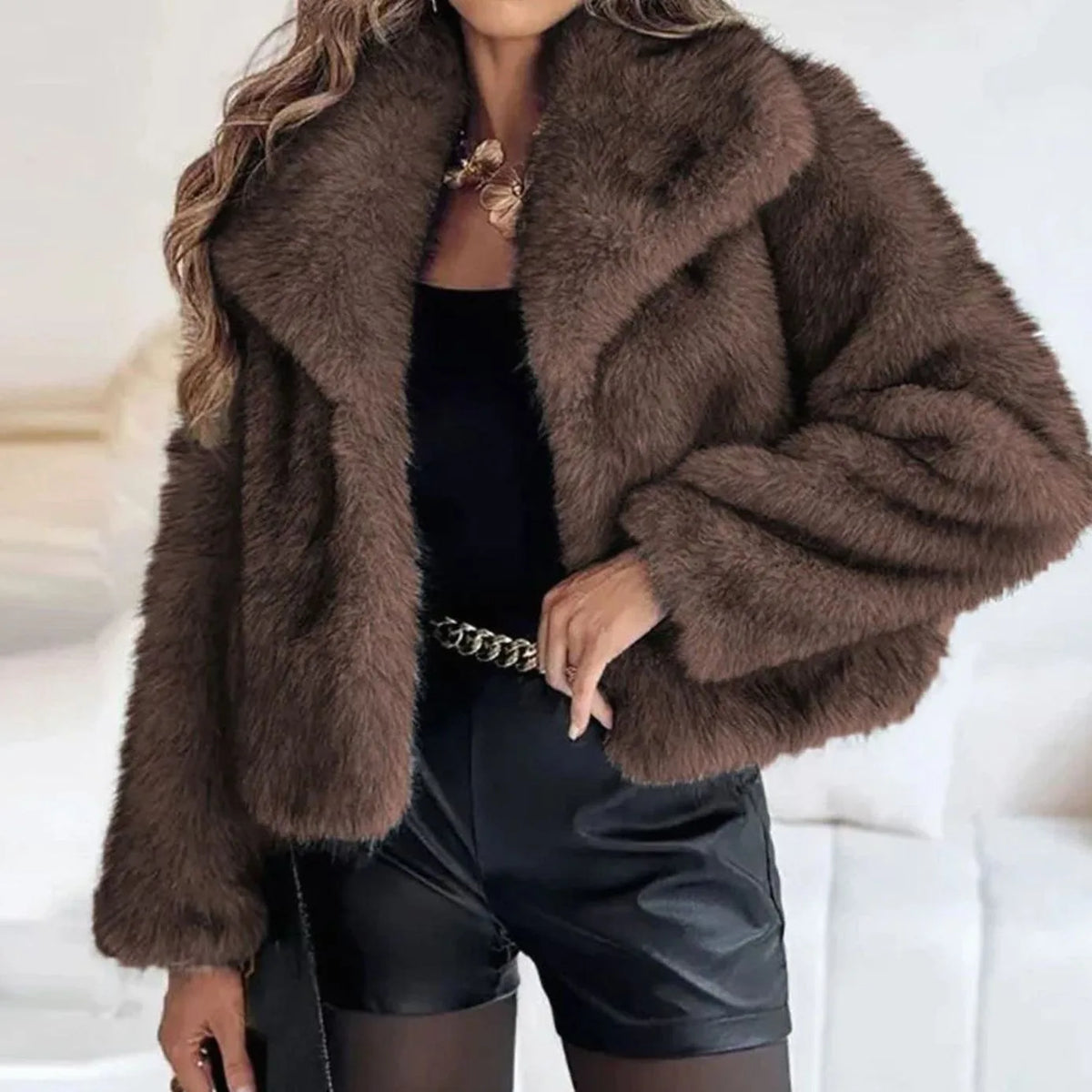 Dark brown faux fur cropped jacket with wide collar, worn open over a black top and satin shorts