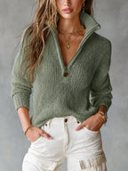 Sage green open-knit half-zip jumper shown close up, collar unzipped over white jeans