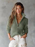 Front view of a woman wearing a sage green open-knit half-zip jumper with collar standing against a grey backdrop
