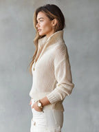 Side profile of a beige open-knit jumper showing the ribbed collar standing upright