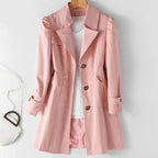 Pink tailored trench coat with notch lapel and shoulder detailing, shown open over a white top on a hanger