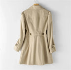 Back view of a beige trench coat showing the fitted waist tab and back vent pleat detail