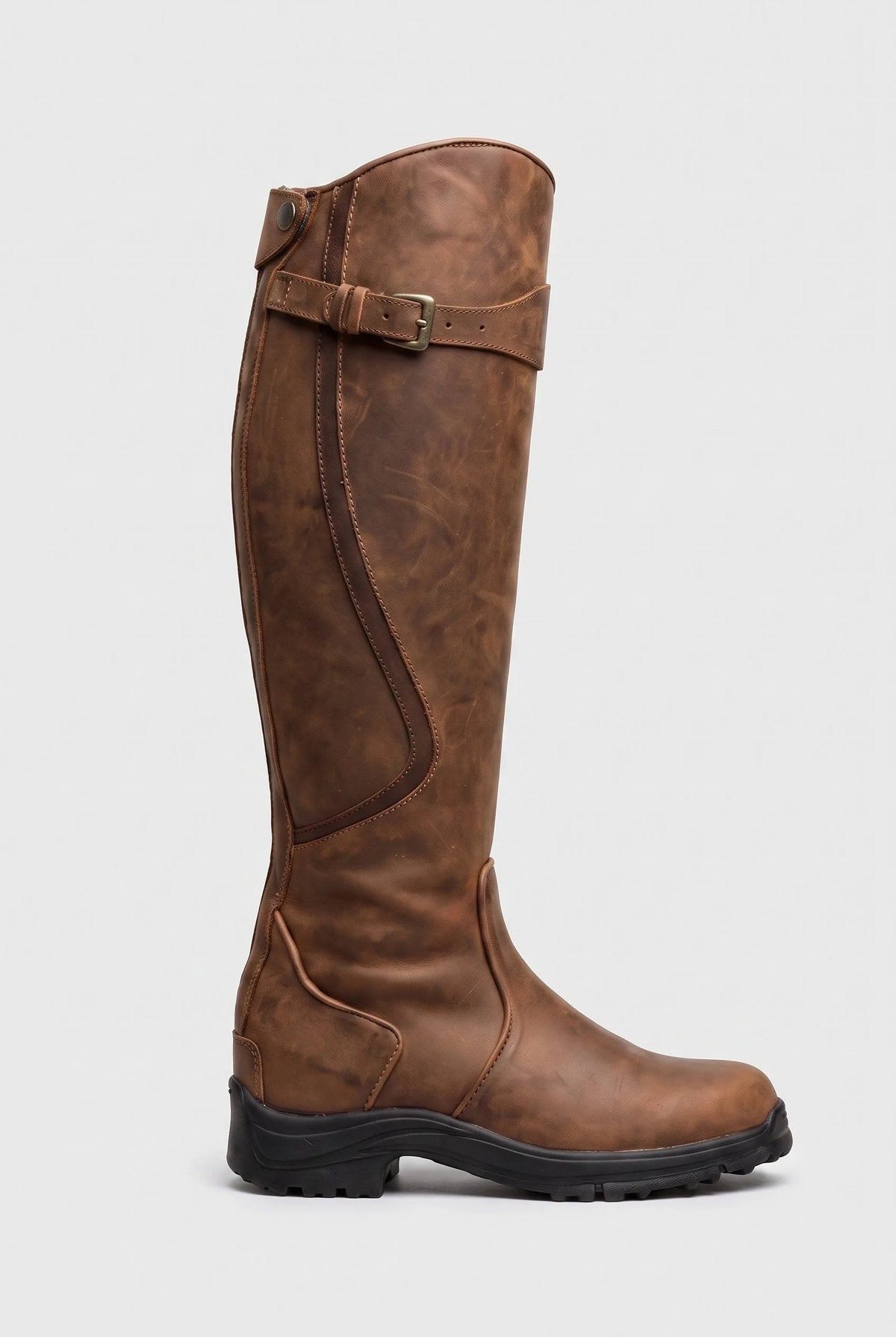 Side view of a tan brown knee-high leather boot with contrast stitching, buckle strap and grippy lug sole