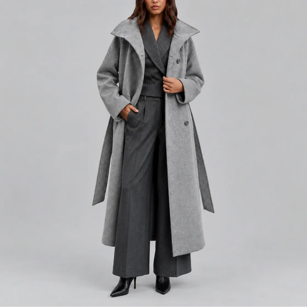 Grey belted longline coat worn open over a pinstripe waistcoat and wide-leg trousers