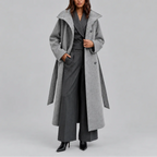 Grey belted longline coat worn open over a pinstripe waistcoat and wide-leg trousers